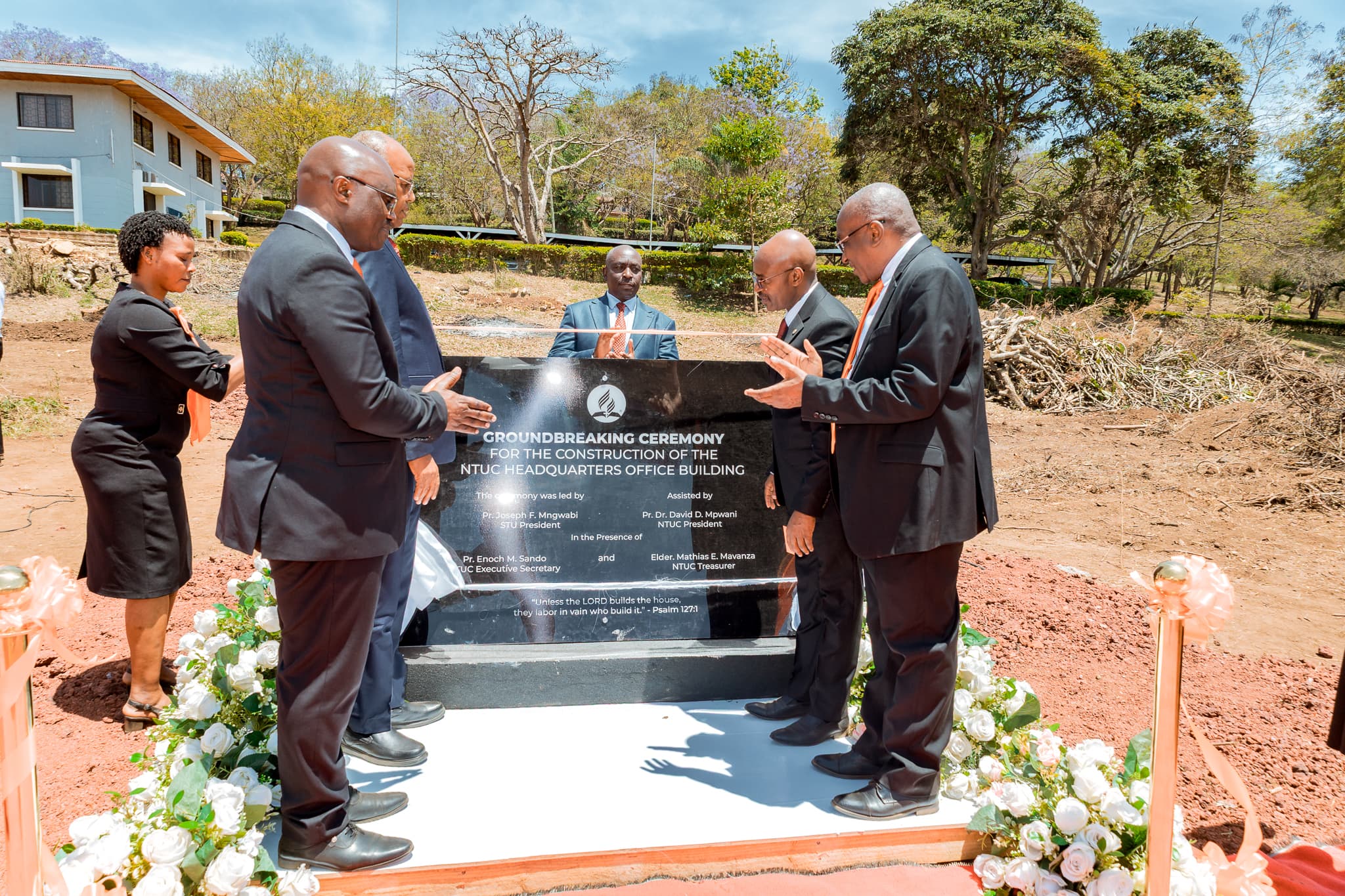 Leaders gathered around the ceremony plaque